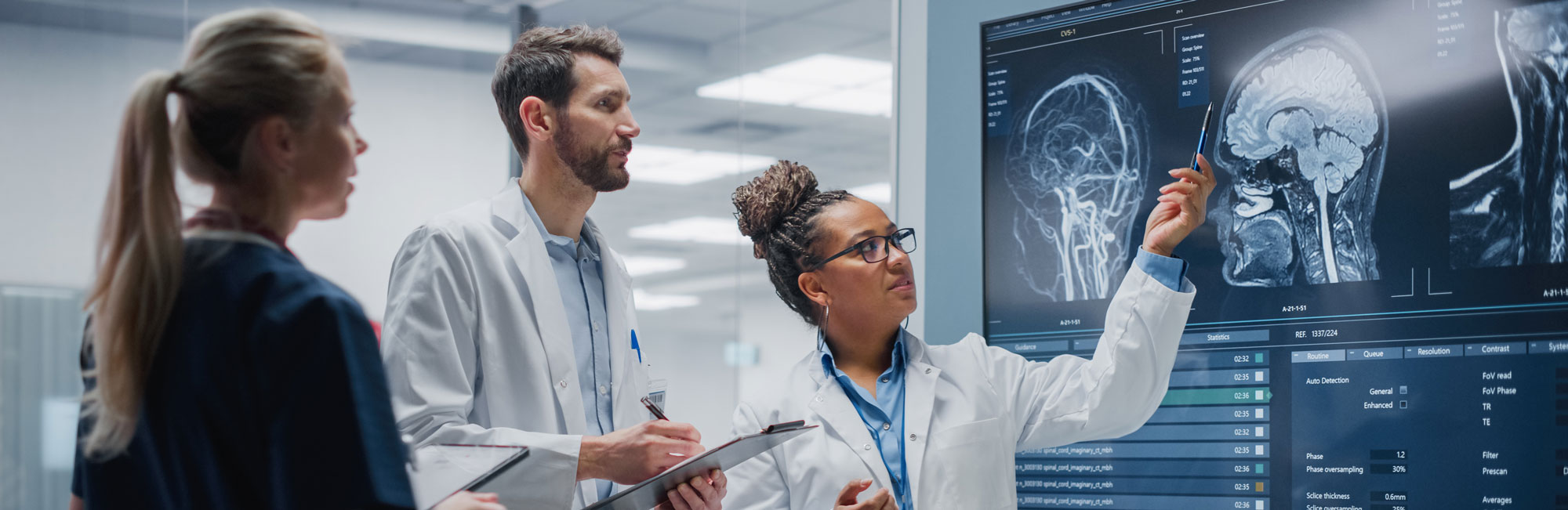 Three medical people examining xrays