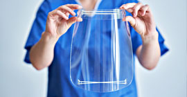 Nurse holding up plastic mask covering