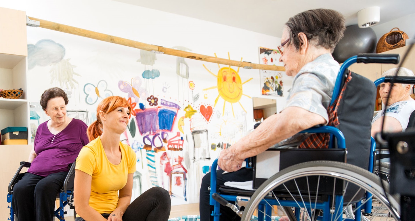 Young female care provider helping a senior man in a wheelchair